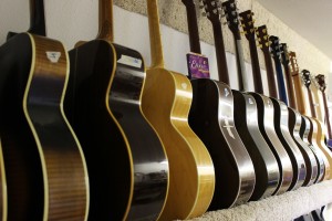 Repaired acoustic guitars on shelf in Lake Oswego, OR shop