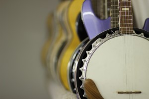 Banjo lined up with other guitars on shelf