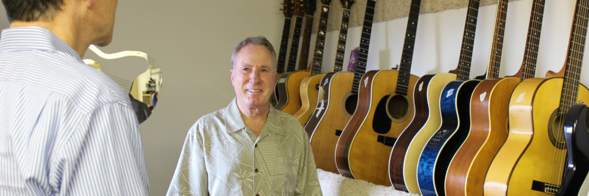 Barrett Coughlan standing next to guitars in Lake Oswego instrument repair shop